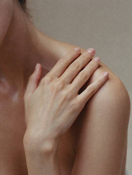 Hand ruht auf dem Schlüsselbein, warmes Licht